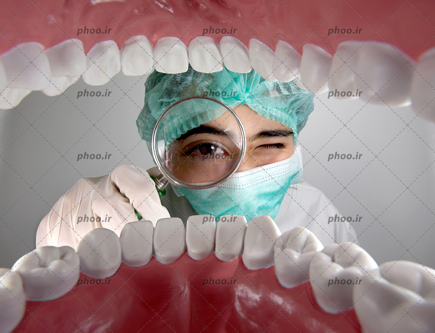 عکس با کیفیت ذره بین در دست پزشک و در حال معاینه دندان های فرد و دندان های سفید و سالم و درخشان