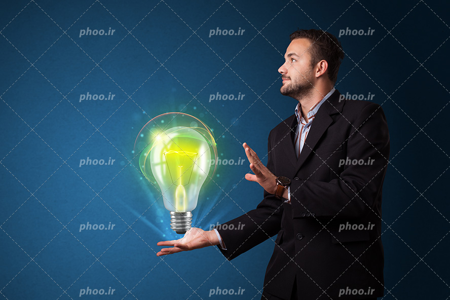 عکس با کیفیت لامپ نورانی در دست مرد با کت و شلوار شیک و پس زمینه به رنگ سرمه ای