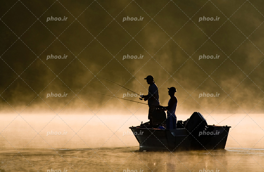 عکس با کیفیت دو مرد ماهیگیر سوار بر قایق در حال ماهیگیری و آسمان در حال غروب