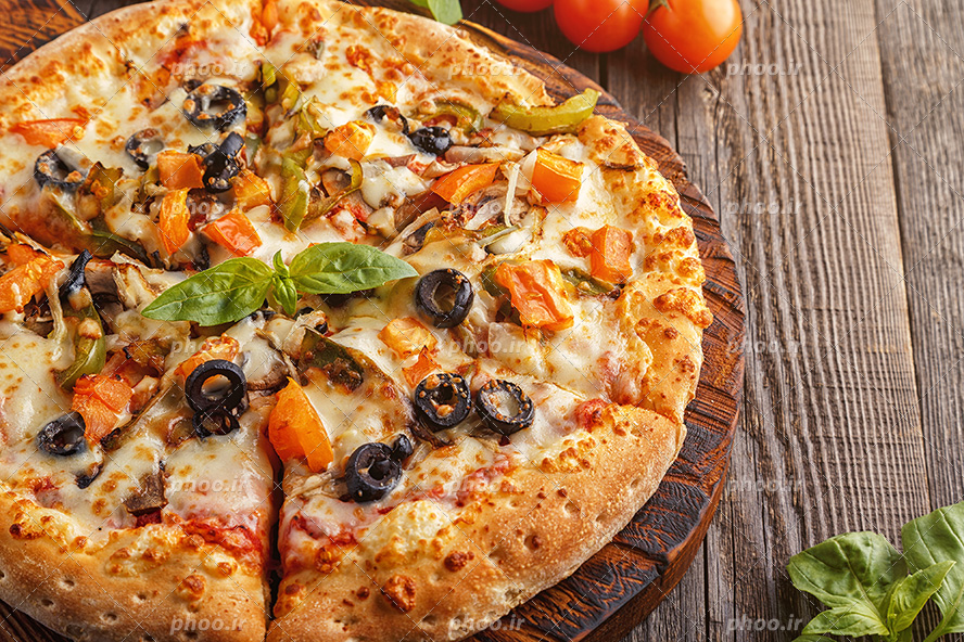 عکس با کیفیت پیتزا خوش رنگ و خوش طعم و لذیذ تزئین شده با گوجه و زیتون سیاه و برگ ریحان