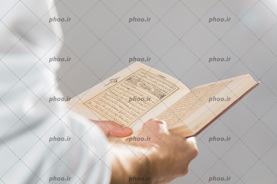عکس با کیفیت قرآن کریم در دست مرد و در حال خواندن قرآن
