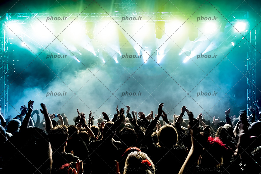 عکس با کیفیت رقص نور های آبی و بخارو دود در کنسرت و مردم در حال شادی و رقص