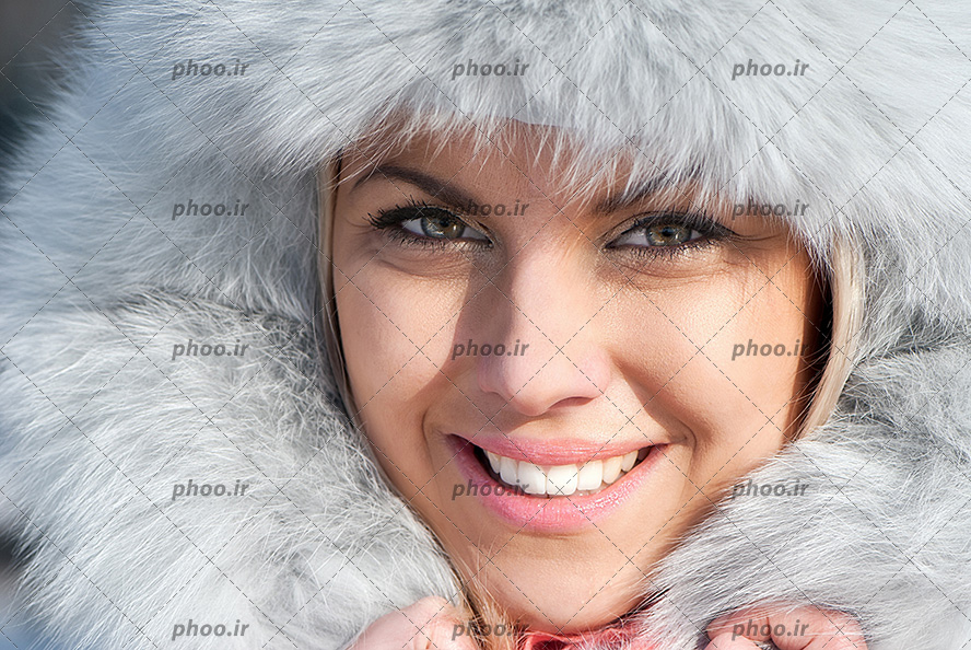 عکس با کیفیت زن با چهره ی خندان و کلاه خزدار به رنگ سفید