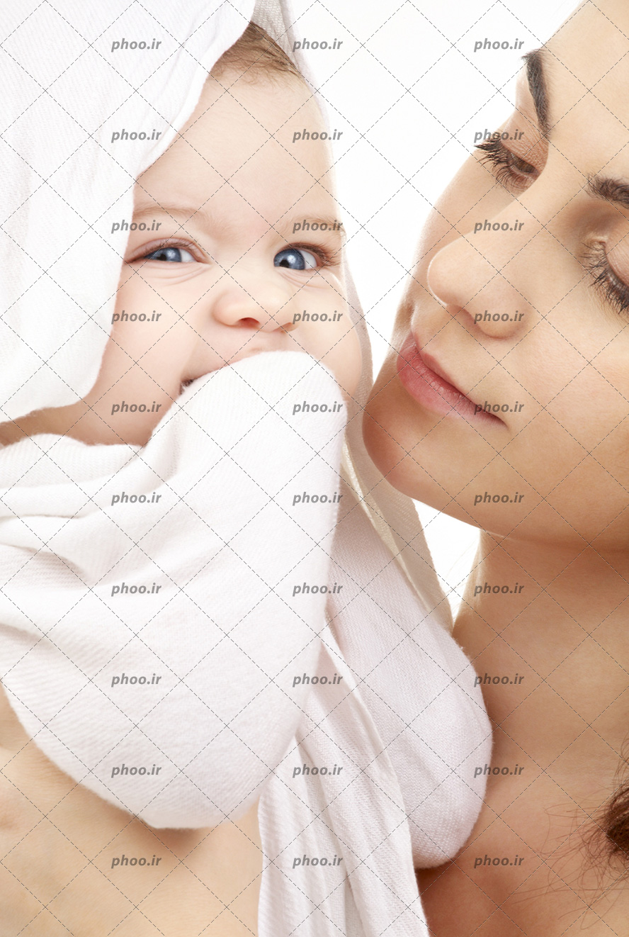 عکس با کیفیت مادر در حال نگاه کردن به نوزاد زیبا با چشم های آبی به همراه حوله حمام