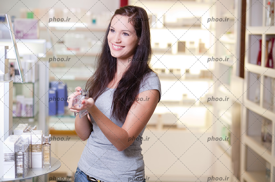 عکس زن جوان زیبا در فروشگاه عطر و ادکلن در حال خرید عطر