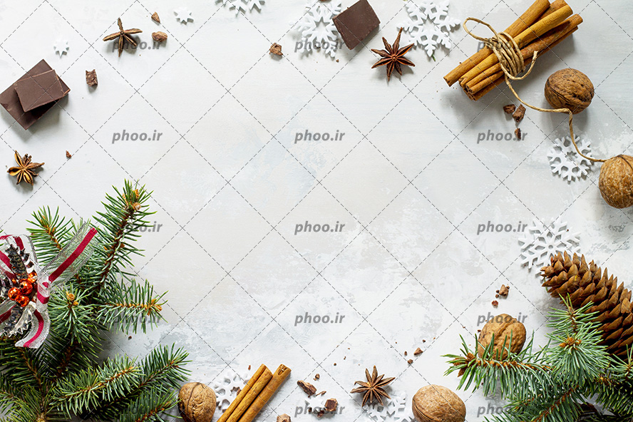 عکس شکلات و گردو و برف تزیینی به همراه بلوط در پس زمینه ای سفید