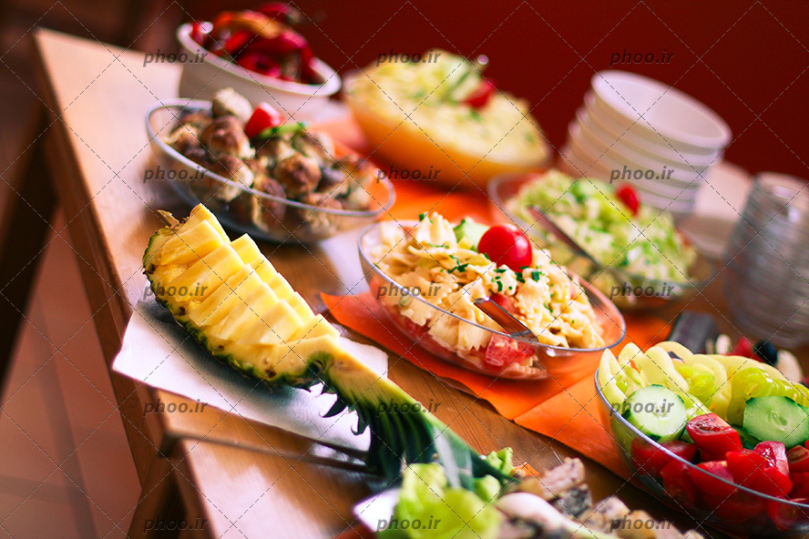 عکس پاستا با سس سبزیجات در ظرف شیشه ای به همراه سالاد روی میز پر از مخلفات