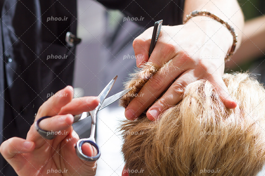عکس با کیفیت آرایشگر در حال کات کردن مو با قیچی و شانه