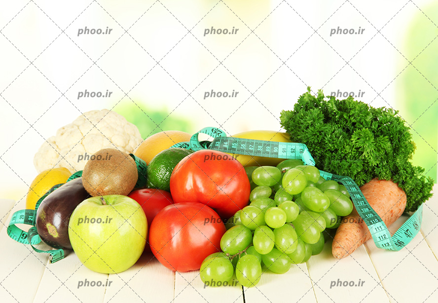 عکس با کیفیت متر اندازه گیری بر روی سبزیجات و میوه های تازه قرار گرفته بر روی میز