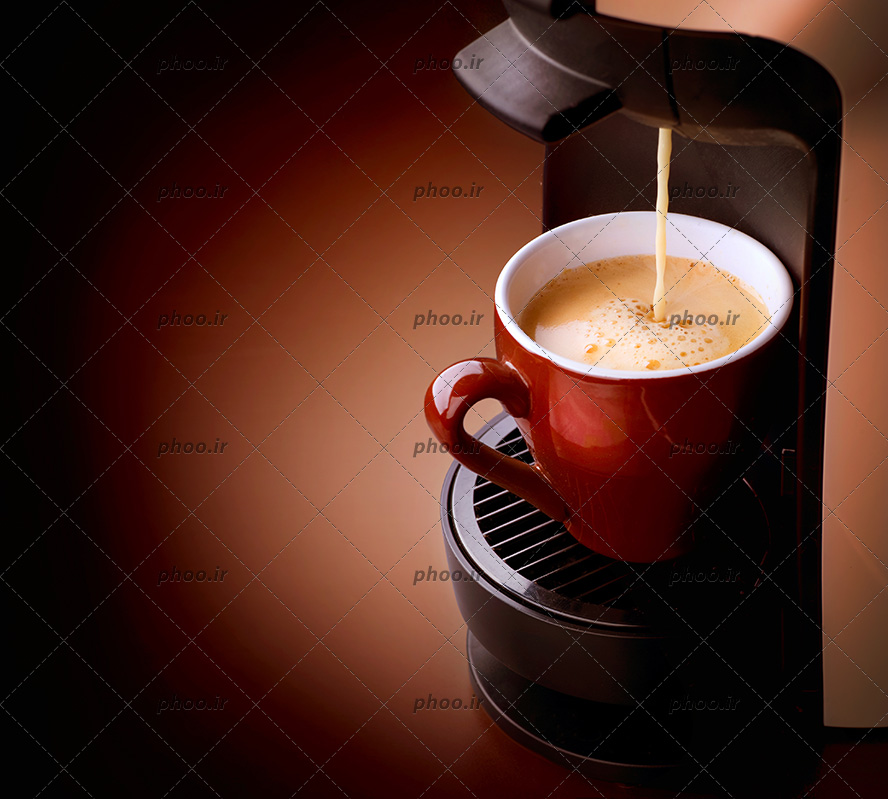 عکس با کیفیت فنجان قرمز در دستگاه قهوه ساز در حال پر شدن قهوه