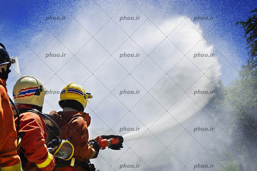 عکس با کیفیت آتش نشان ها در حال خاموش کردن آتش با کمک یکدیگر