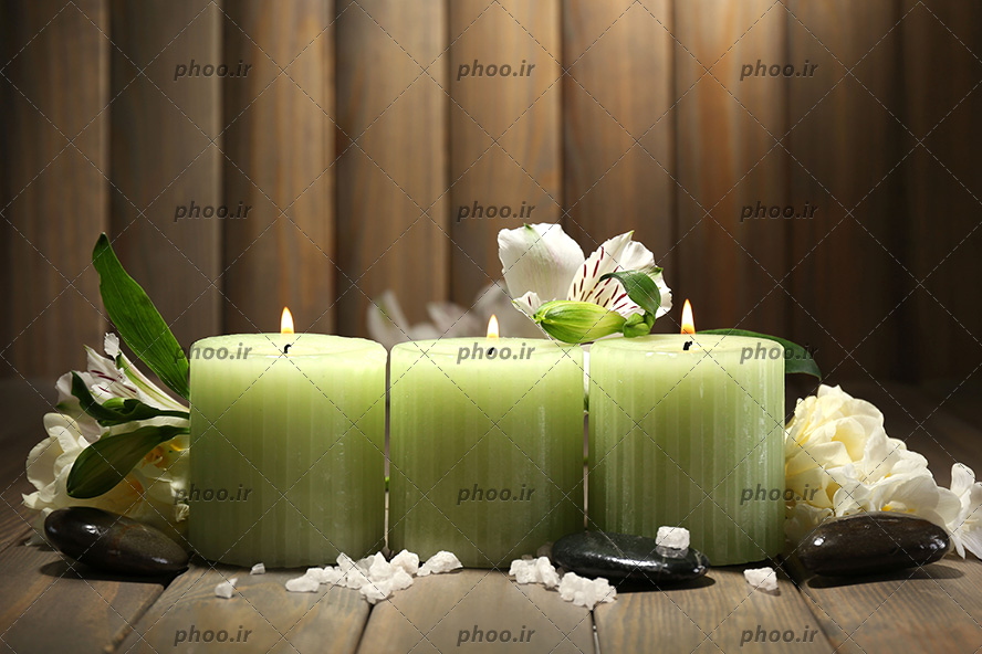 عکس شمع و گل و سنگ برای ماساژ در پس زمینه چوبی