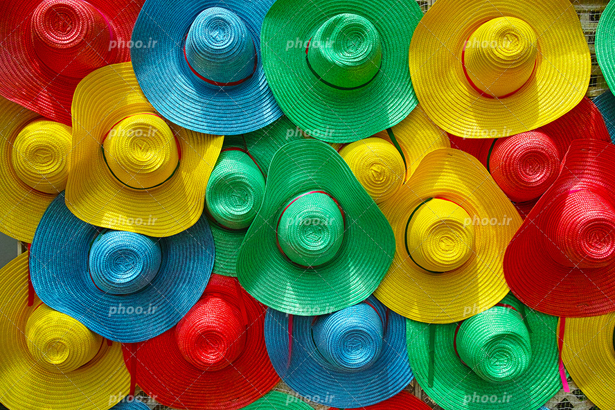 عکس با کیفیت کلاه های ساحلی با رنگ های زیبا چیده شده در کنار یکدیگر