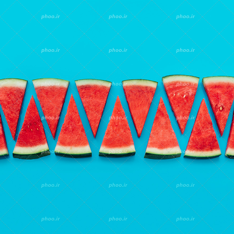 عکس با کیفیت قاچ های هندوانه به شکل مثلث چیده شده در کنار یکدیگر در پس زمینه آبی
