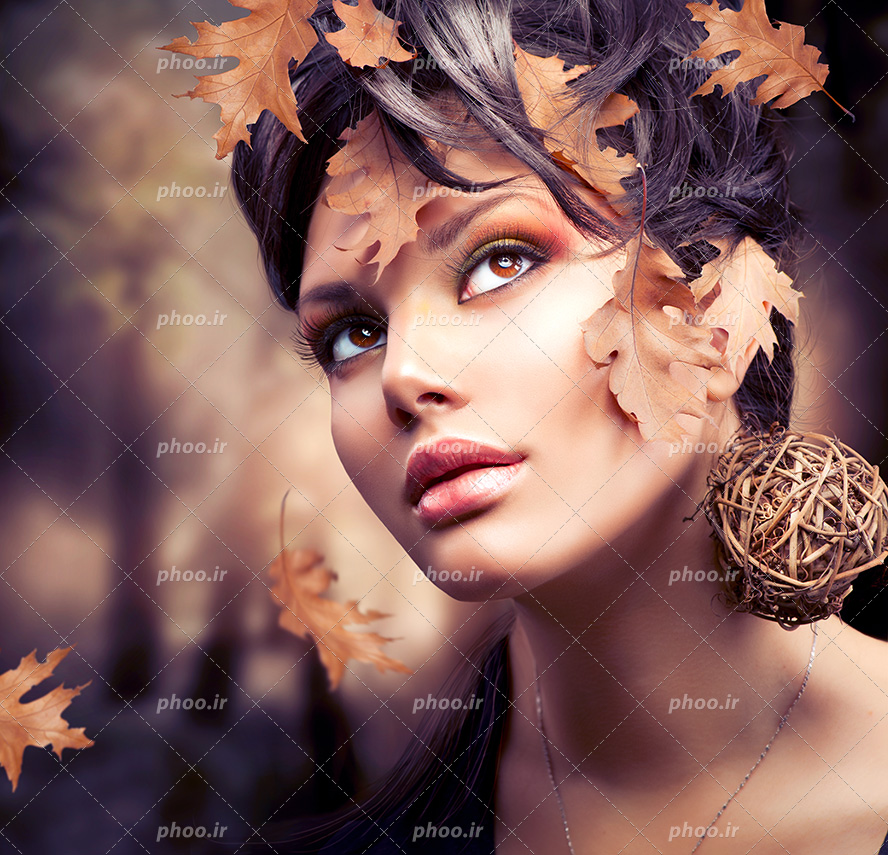 عکس با کیفیت زن با چهره ی نچرال زیبا و موهای مشکی تزئین شده با برگ های پاییزی بر روی موهایش