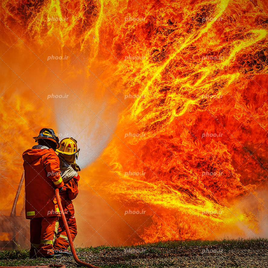 عکس با کیفیت آتش شعله ور به رنگ نارنجی و آتش نشان ها در حال خاموش کردن آتش شعله ور