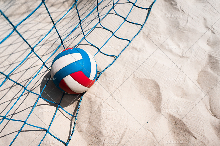 عکس با کیفیت توپ والیبال بر روی تور والیبال و بر روی ماسه های ساحل