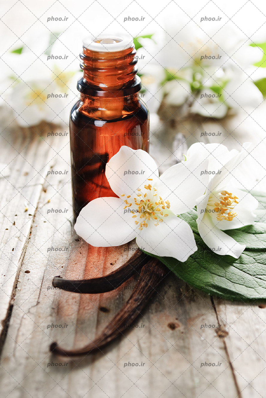 عکس زیبا عصاره گل در بطری شیشه ای روی میز باگل