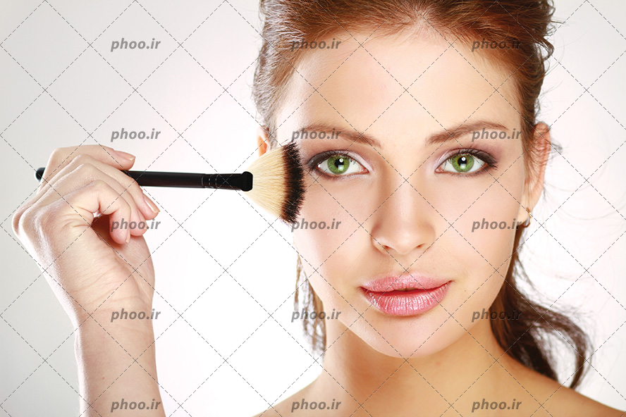 عکس دختر زیبا با چشم های سبز و مو های قهوه ای در حال آرایش کردن صورت