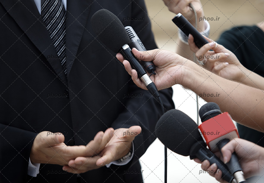 عکس دست های خبرنگاران درحال مصاحبه با مرد با میکروفون