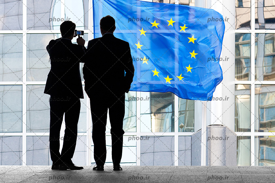 عکس پرچم اتحادیه اروپا و سایه دو مرد جلوی آن